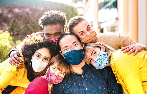 Amigos milenares multiculturais tirando selfie sorrindo por trás de máscaras faciais