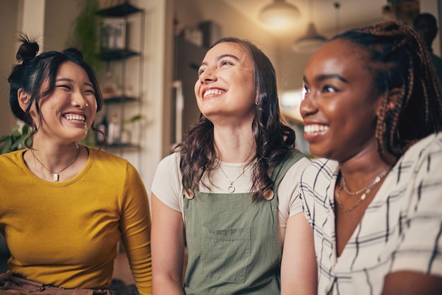 Amigos y mujeres felices en una sala de estar con conversaciones divertidas y vínculos en su hogar juntos. Sonrisas de chismes y personas con diversidad en una casa para el fin de semana de reunión y relajarse en el día libre.