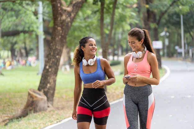 Amigos de las mujeres jóvenes para correr juntos en el parque. Corredoras escuchando música mientras corren.