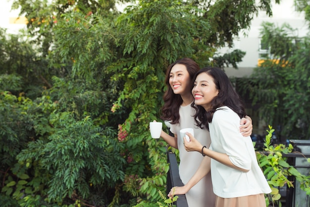 Amigos de las mujeres jóvenes felices bien vestidos sonriendo mientras están parados juntos