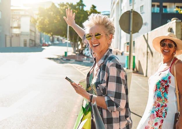 Amigos mujeres mayores y viajes de aventura en la ciudad y felicidad libertad al aire libre con una sonrisa Feliz jubilación y vacaciones en la calle urbana de California y teléfono con gafas de sol de moda y maqueta