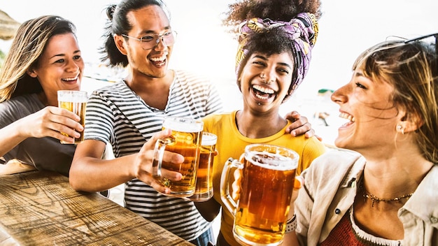 Amigos multiculturais torcendo copos de cerveja juntos lá fora