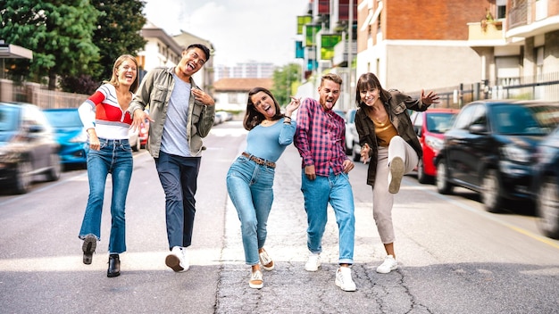 Amigos multiculturales de moda caminando en el centro de la ciudad jugando divertidos movimientos locos