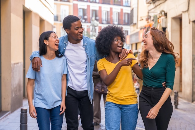 Amigos multiétnicos abrazados sonriendo caminando por el estilo de vida de la ciudad