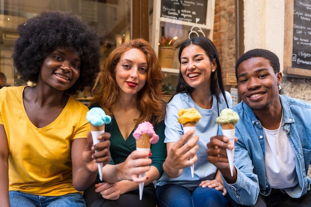 Amigos multiétnicos em uma sorveteria comendo um sorvete divertido de verão olhando para a câmera