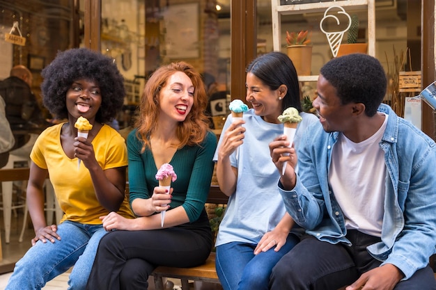 Amigos multiétnicos em uma sorveteria sentado comendo um sorvete rindo muito