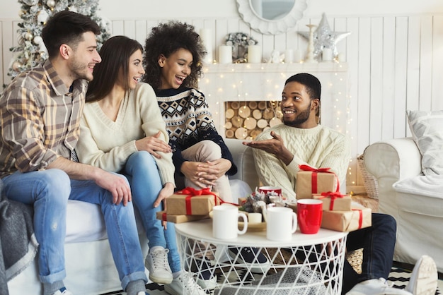 Amigos multiétnicos felices hablando en casa, celebrando la Navidad juntos, espacio de copia