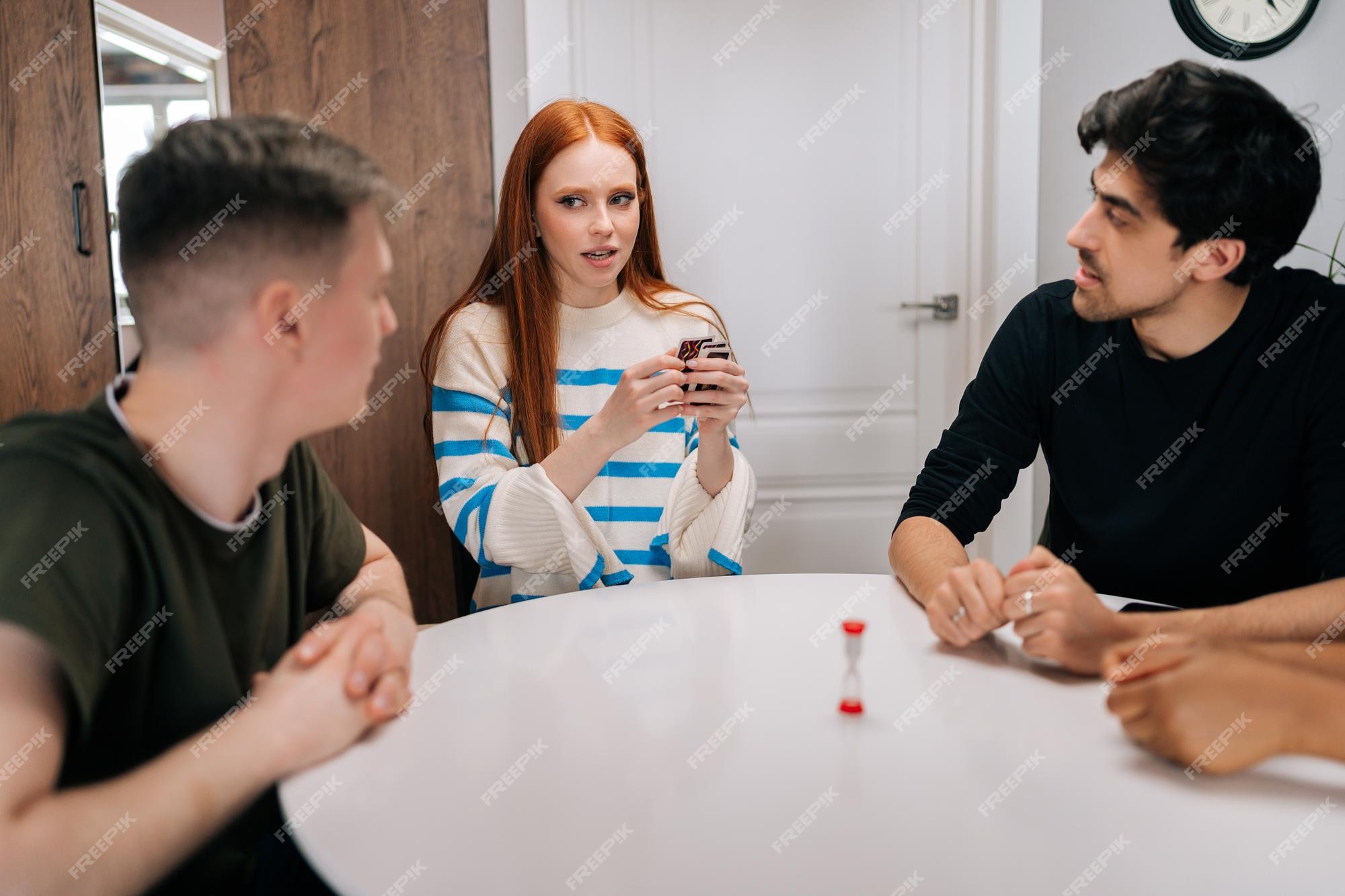 Amigos multiétnicos felizes tendo jogos de cartas por tempo