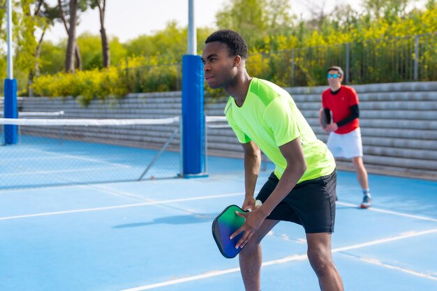 Amigos multiétnicos jugando pickleball juntos en un día soleado