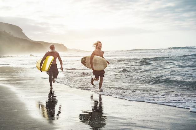 Amigos multigeneracionales que van a surfear en una playa tropical