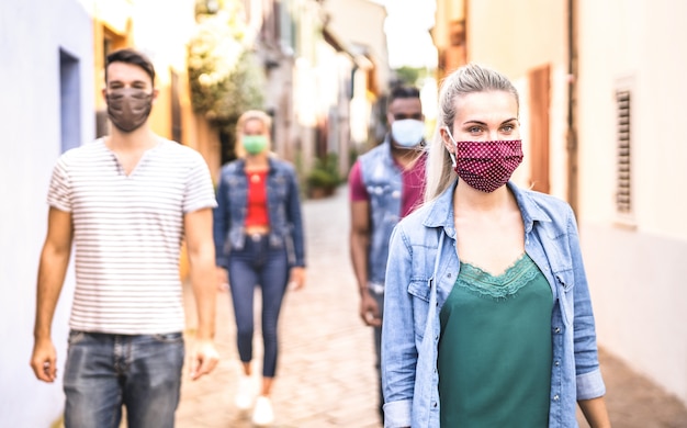 Foto amigos multirraciais andando com máscara facial após reabertura do bloqueio - foco seletivo na mulher certa