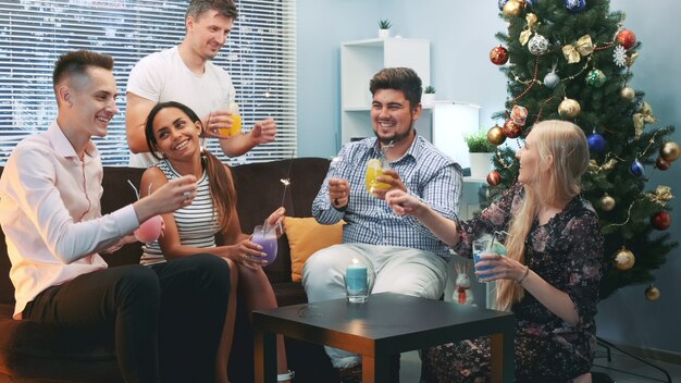 Amigos multirraciais comemorando as férias de inverno com estrelinhas e coquetéis