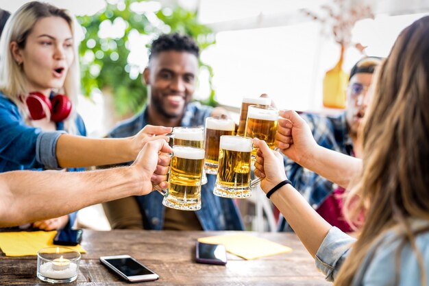 Amigos multirraciais felizes bebendo e brindando cerveja no bar da cervejaria