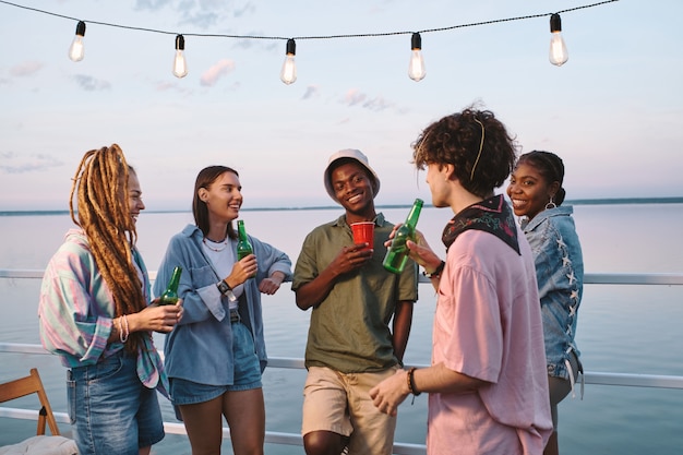 Amigos multirraciais felizes com bebidas em uma festa ao ar livre