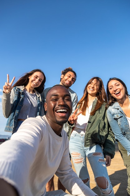 Amigos multirraciais sorridentes tiram selfie olhando para a câmera Copie o espaço Imagem vertical Amizade e conceito de mídia social