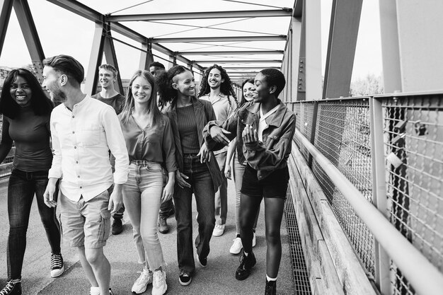 Amigos multirraciales divirtiéndose al aire libre caminando por el puente Enfoque en la cara de niña centroafricana Edición en blanco y negro