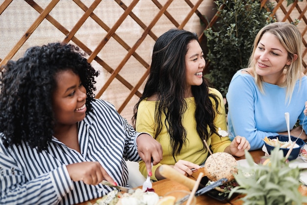 Amigos multirraciales felices desayunando al aire libre en el restaurante del patio - Enfoque principal en la cara de la niña asiática