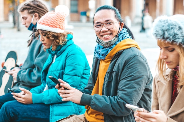 Amigos multirraciales que usan teléfonos móviles para rastrear la propagación del coronavirus