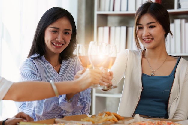 Amigos na festa de aniversário tilintando copos com champanhe e pizza desfrutando de pizza de férias de Natal na mesa Evento de festa de fim de ano