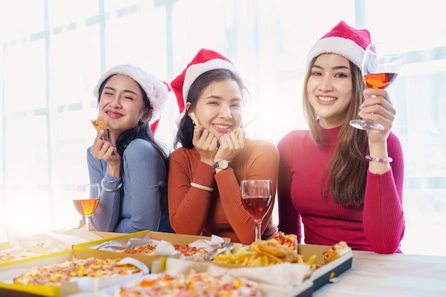 Amigos na festa de aniversário tilintando copos com champanhe e pizza desfrutando de pizza de férias de Natal na mesa Evento de festa de fim de ano