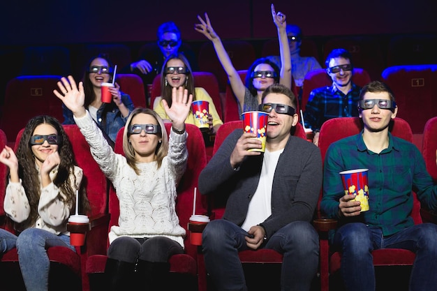 Amigos no cinema assistem a um filme engraçado com óculos 3D riem se divertem