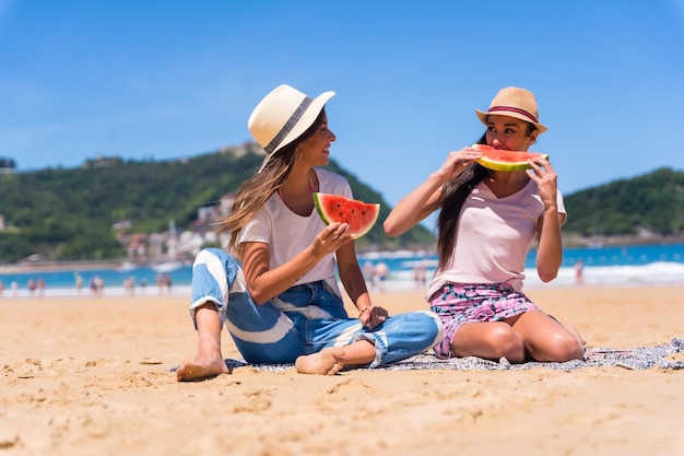 Amigos no verão na praia comendo uma melancia