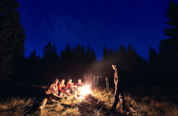 Amigos passam uma noite queimando fogo no acampamento na floresta