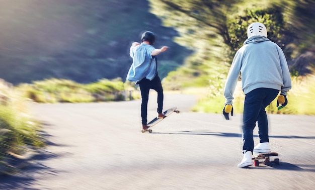 Amigos de patinaje de velocidad y longboard en carretera hombres corriendo cuesta abajo con monopatín y casco por seguridad Deportes extremos aventura skateboarding carrera callejera y trucos de skater en paso de montaña