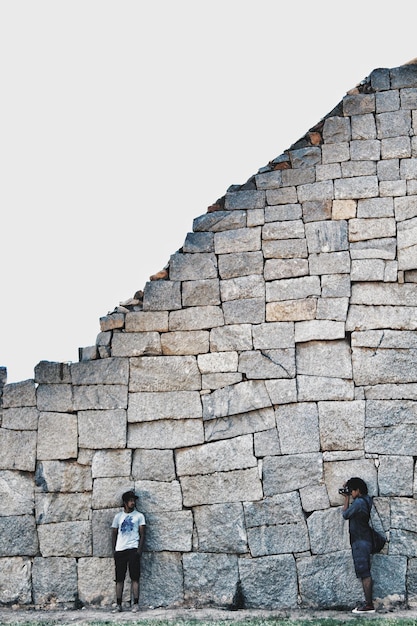 Foto amigos de pie contra una pared de piedra