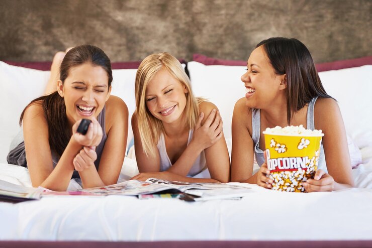 Foto amigos pipocas e rir para dormir social e quarto para ligação e grupo emocionado para lanches pessoas femininas juntos e revistas para piadas amigas e entretenimento com conversa