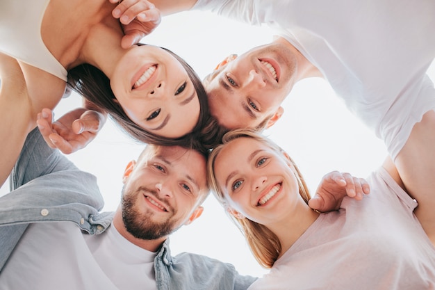 Amigos positivos, segurando suas cabeças perto um do outro e olhando para baixo