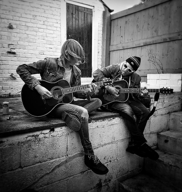 Foto amigos practicando la guitarra mientras están sentados en el porche
