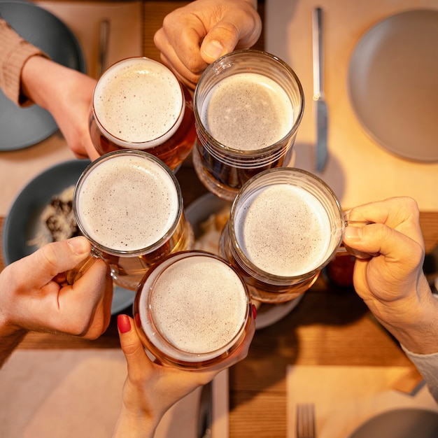 Foto amigos de primer plano sosteniendo jarras de cerveza en el pub