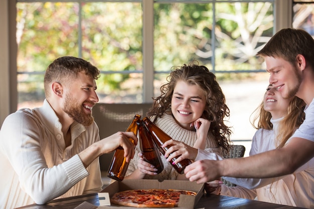 amigos quatro dois homens e duas mulheres felizes juntos na mesa comendo pizza