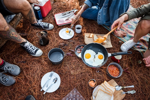 Amigos que acampam comendo o conceito do alimento