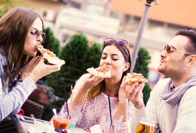 Amigos que comem a pizza