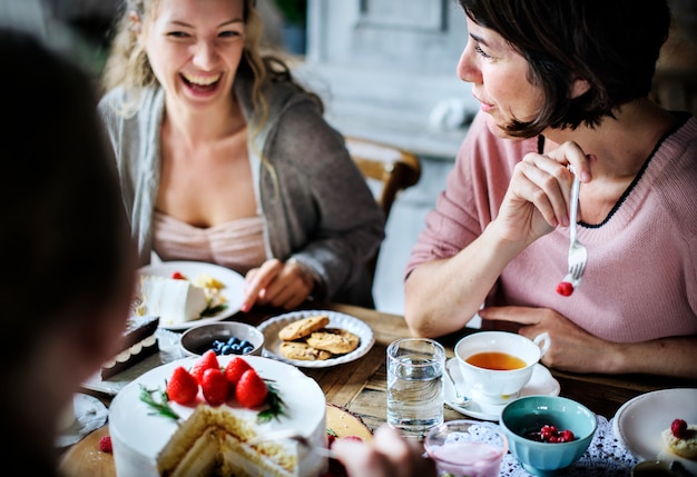 Foto amigos que se reúnen en la fiesta del té comiendo tortas disfrute la felicidad