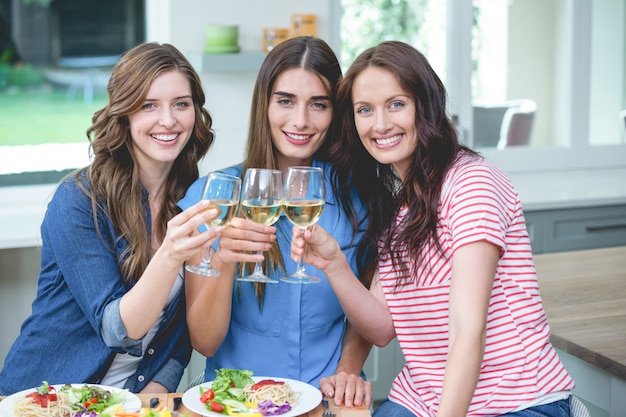 Foto amigos que tuestan una copa de vino mientras comen