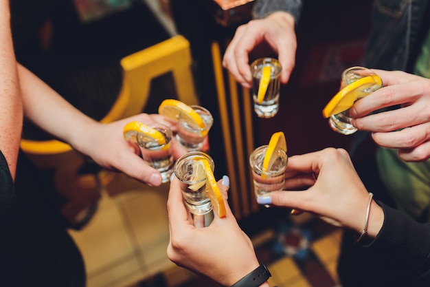 Foto amigos que tuestan con los vasos de medida sobre un viejo fondo negro de la tabla de madera.