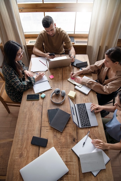 Foto amigos que usan computadoras portátiles y portátiles para aprender en una sesión de estudio