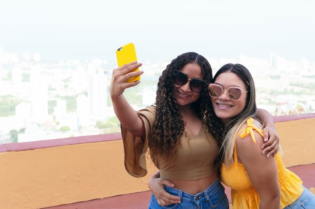 Amigos que usan el teléfono celular. Hermosas novias usando el móvil y riendo. Amigos caminando por la calle con teléfono celular.