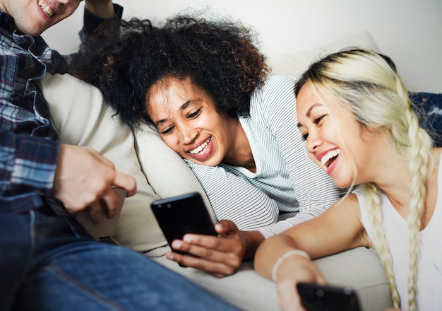 Amigos que usan el teléfono inteligente juntos en casa