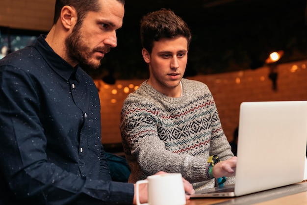 Amigos que utilizan el móvil y la computadora portátil en una cafetería.