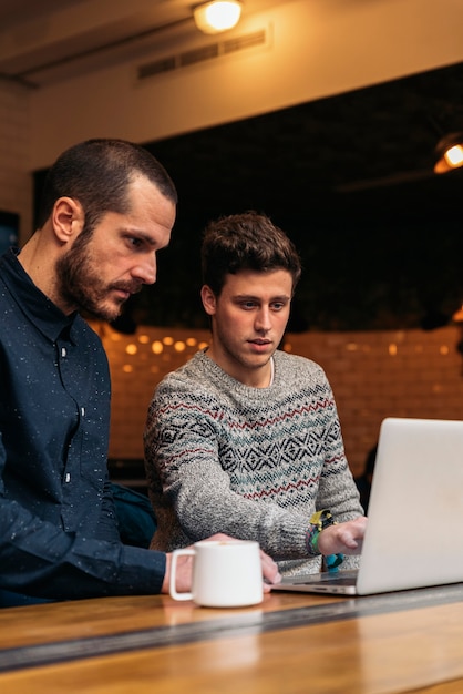 Amigos que utilizan el móvil y la computadora portátil en una cafetería.