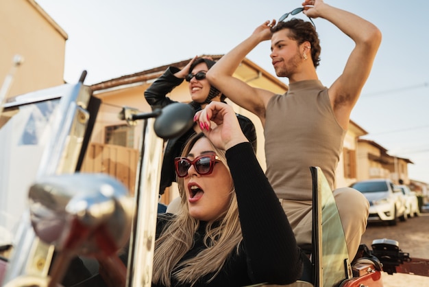 Foto amigos que viajan juntos en un viejo coche descapotable. concepto de disfrute de verano