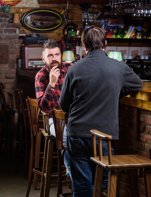 Amigos relaxando no pub Conversa amigável com estranho Hipster brutal homem barbudo passar lazer com amigo balcão de bar no pub Homens relaxando no pub Lazer de fim de semana Relaxamento de sexta-feira no pub