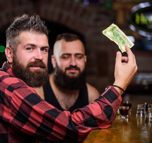 Amigos relaxando no pub. Homem barbudo brutal hipster passar lazer com amigo no balcão de bar. Peça bebidas no balcão do bar. Homens relaxando no bar. Amizade e lazer. Relaxamento de sexta-feira no bar.