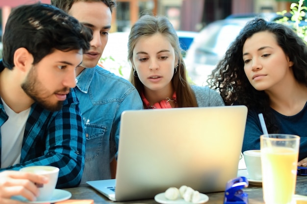 Amigos reunidos en una cafetería con un ordenador portátil.