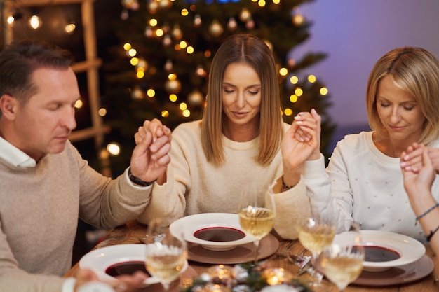 Amigos rezando antes do jantar de Natal. Foto de alta qualidade