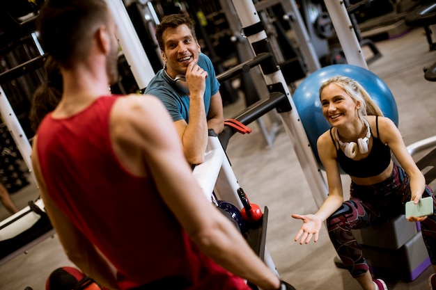 Amigos en ropa deportiva hablando juntos mientras están de pie en un gimnasio después de un entrenamiento